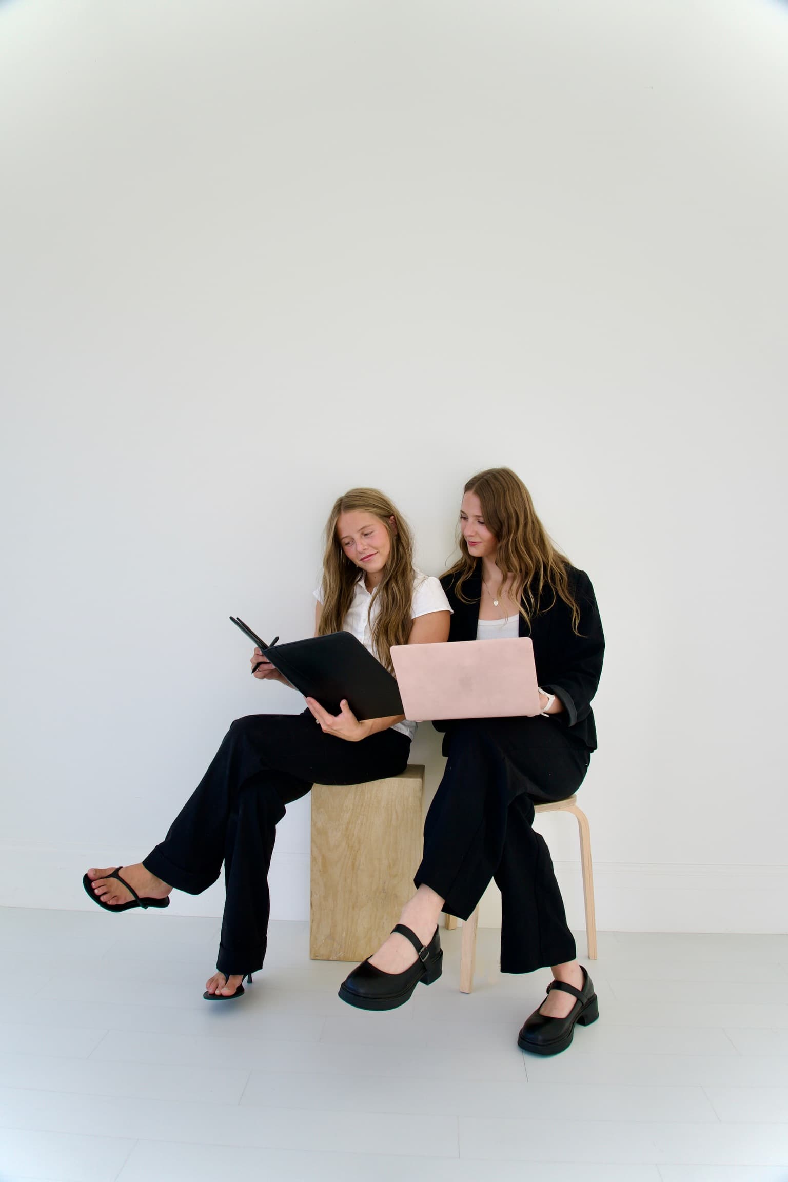 The two founders of Marie Kate Events, each holding a laptop